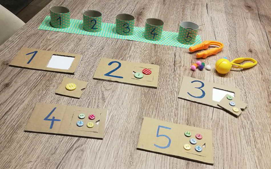 Hat ein Kind Freude am Zählen, dann kann dieses Zahlenpuzzle mit ganz einfachen Mit-teln hergestellt werden. Karton, Klopapierrollen, Knöpfe sind die Grundmaterialien dieses Lernarrangements. (Anna Werndl)